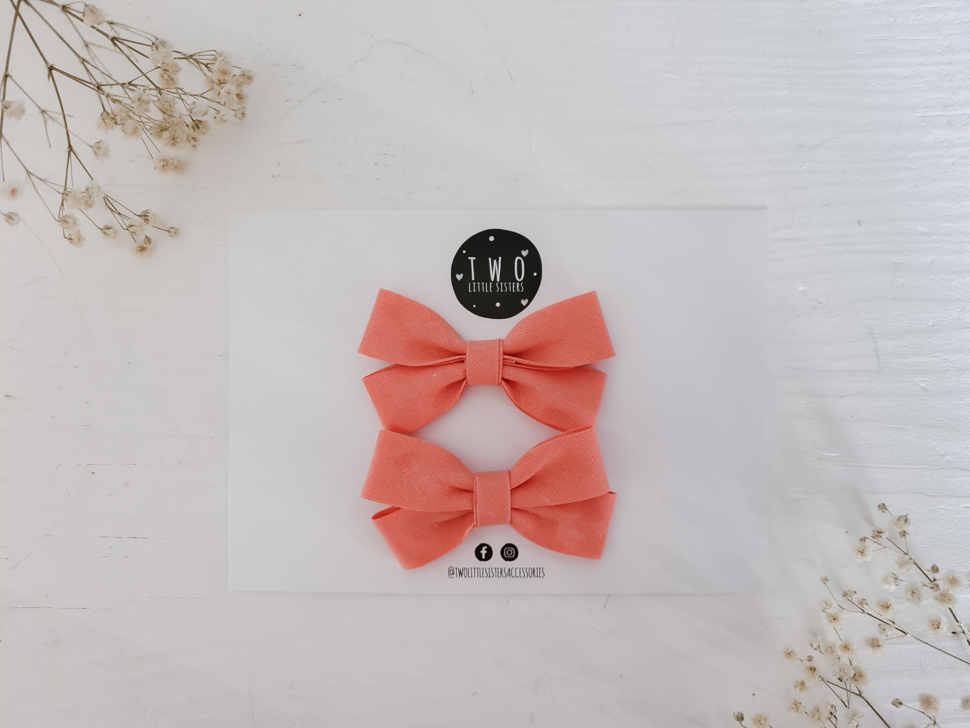 Dois laços cor de salmão em base com logotipo TWO Accessories