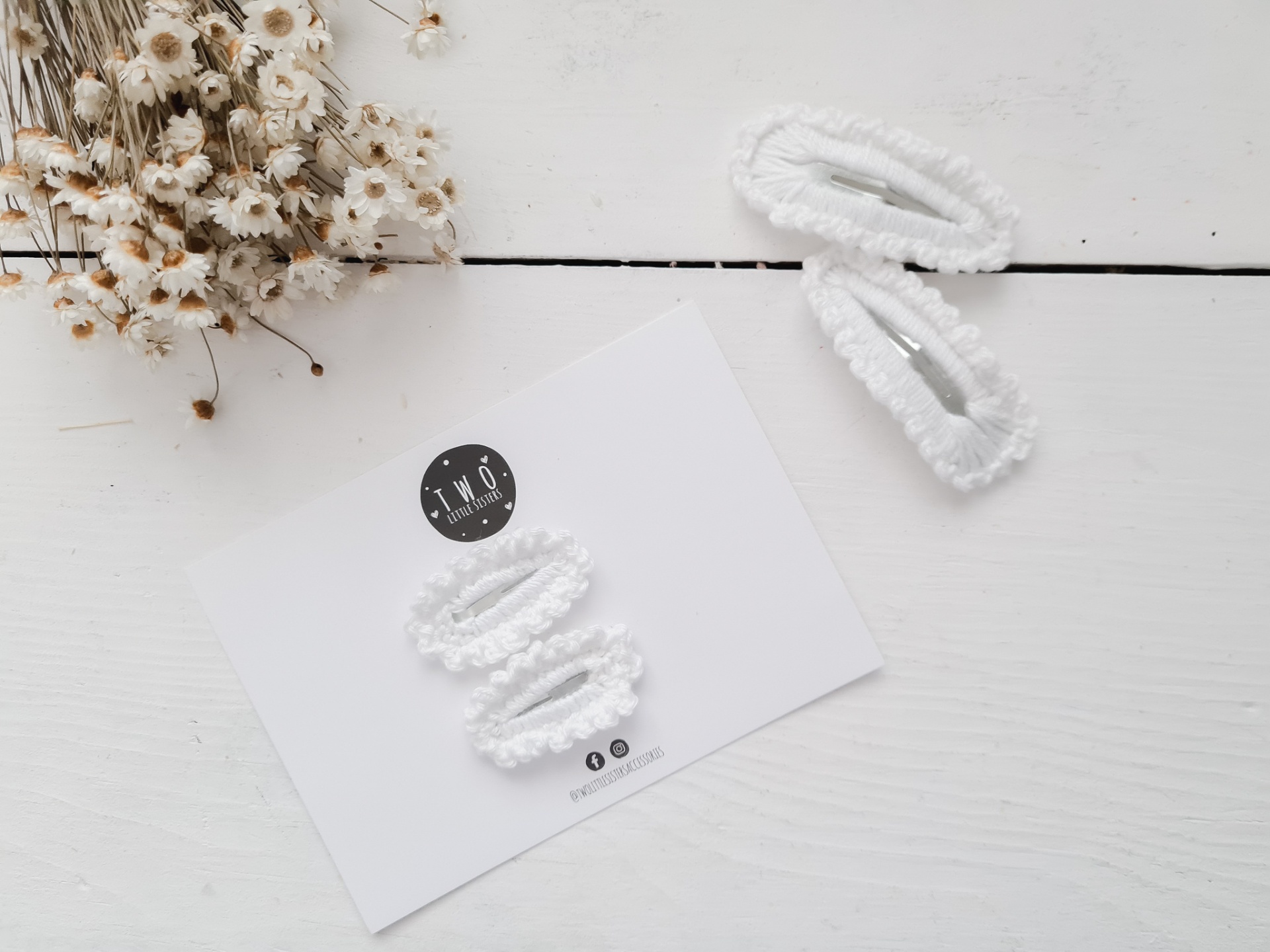 ganchos de cabelo brancos com textura frisada sobre cartão branco e flores secas