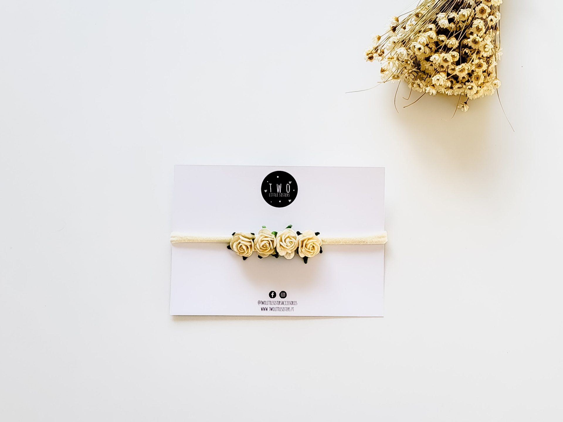 Pulsera com flores bege sobre cartão branco com logotipo preto e ramo seco ao lado