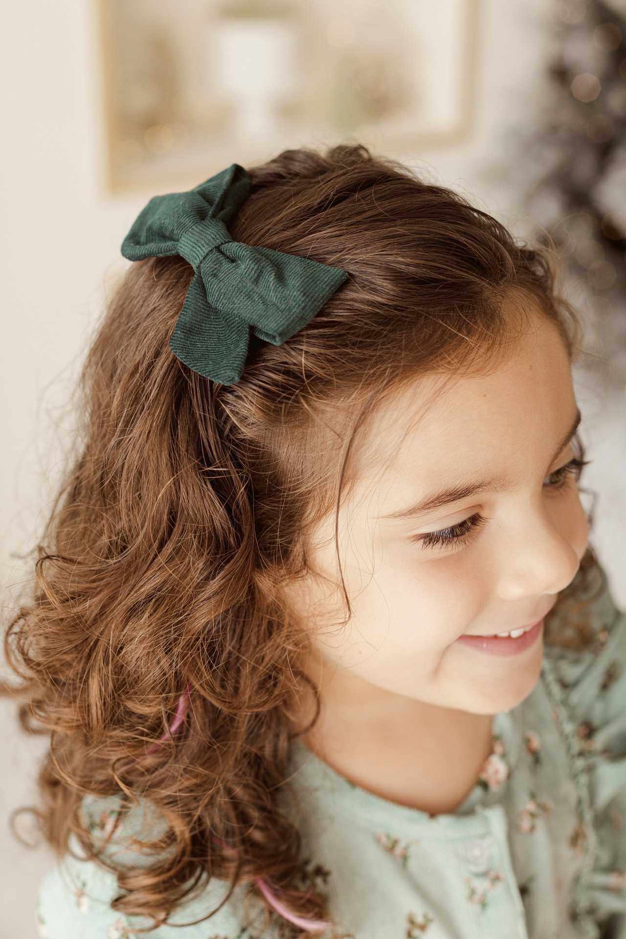 Laço verde escuro no cabelo encaracolado de menina