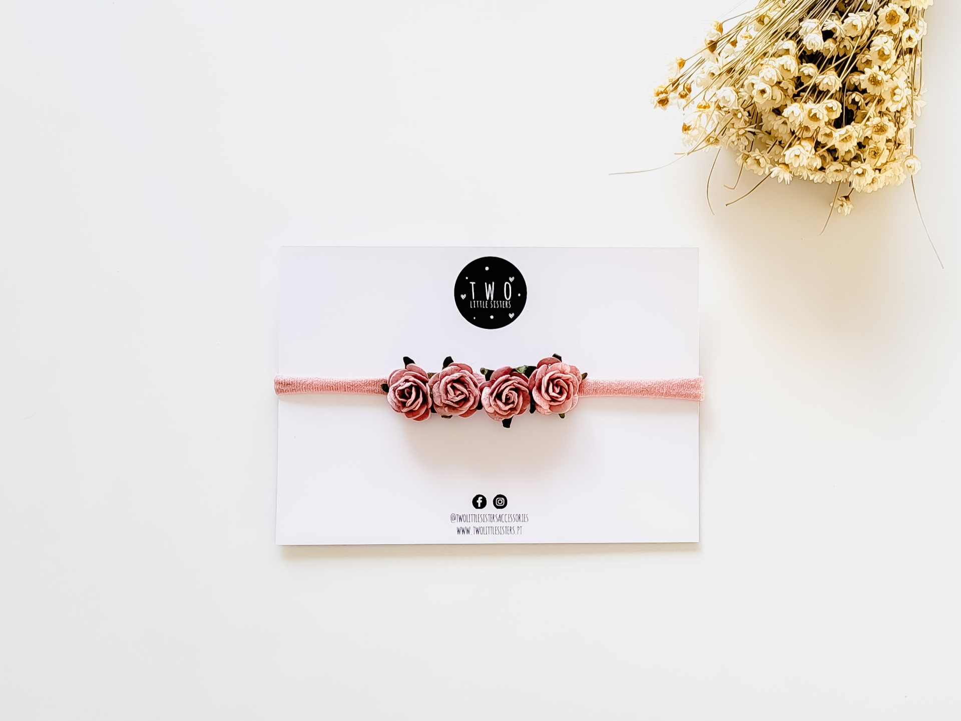 Faixa de cabelo rosa com flores cor-de-rosa em cartão branco e flores secas ao lado