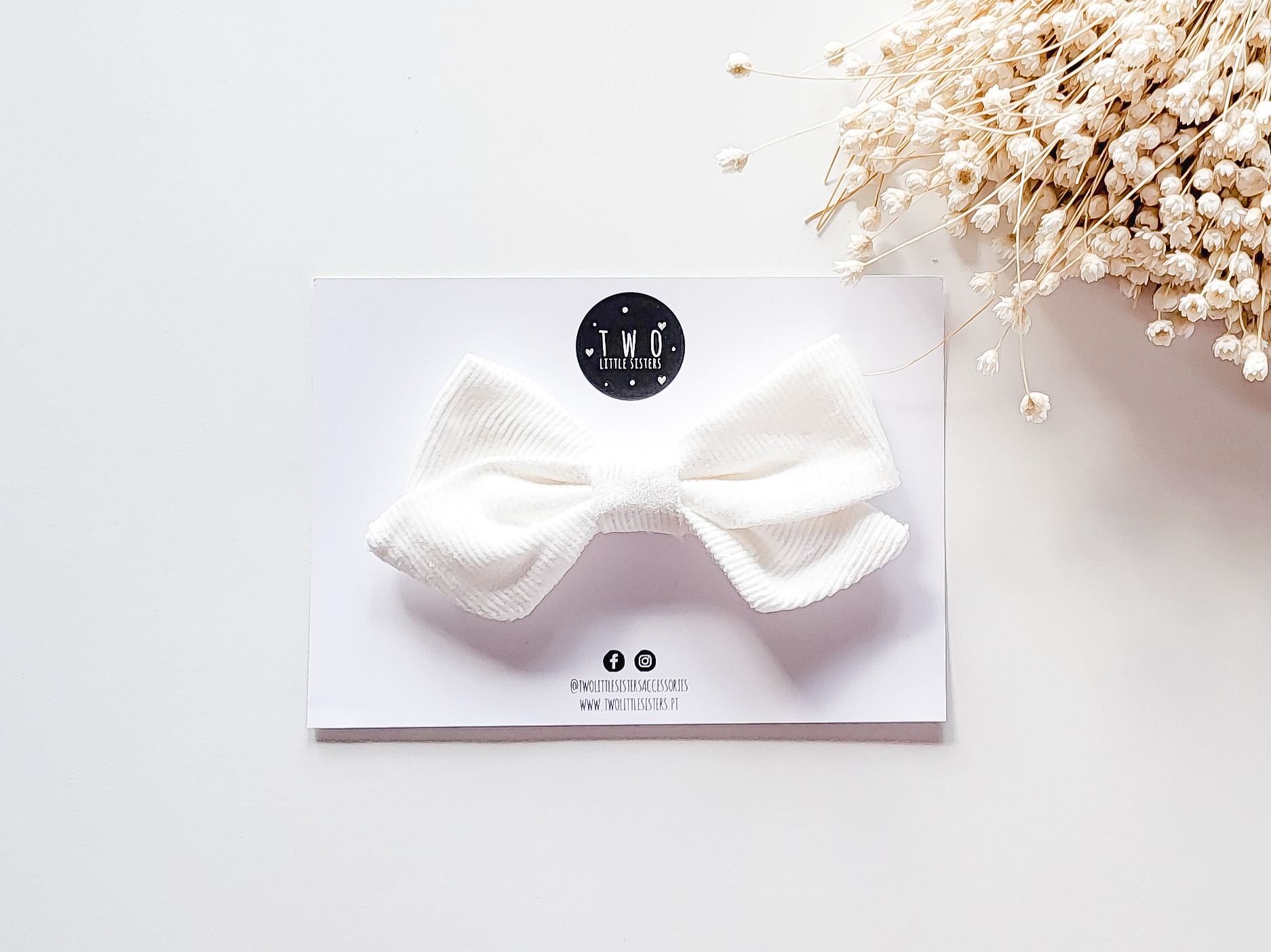 Laço branco de tecido sobre cartão com logotipo T.M.O ACCESSORIES