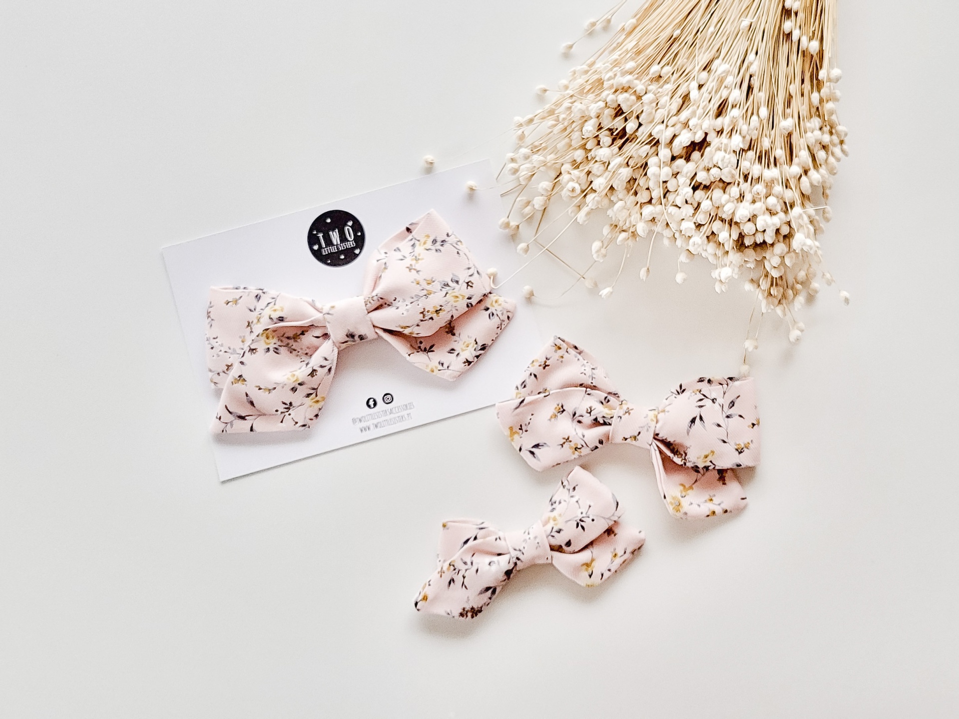 Laços de cabelo rosa com padrão floral e flores secas brancas