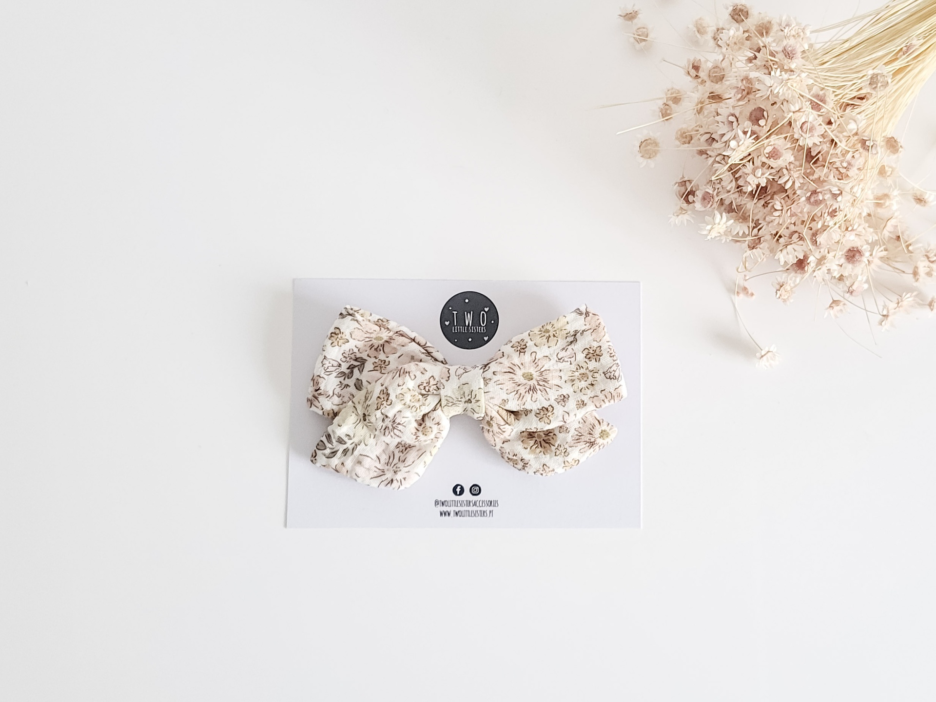 Laço de cabelo floral em cartão branco com flores secas ao lado