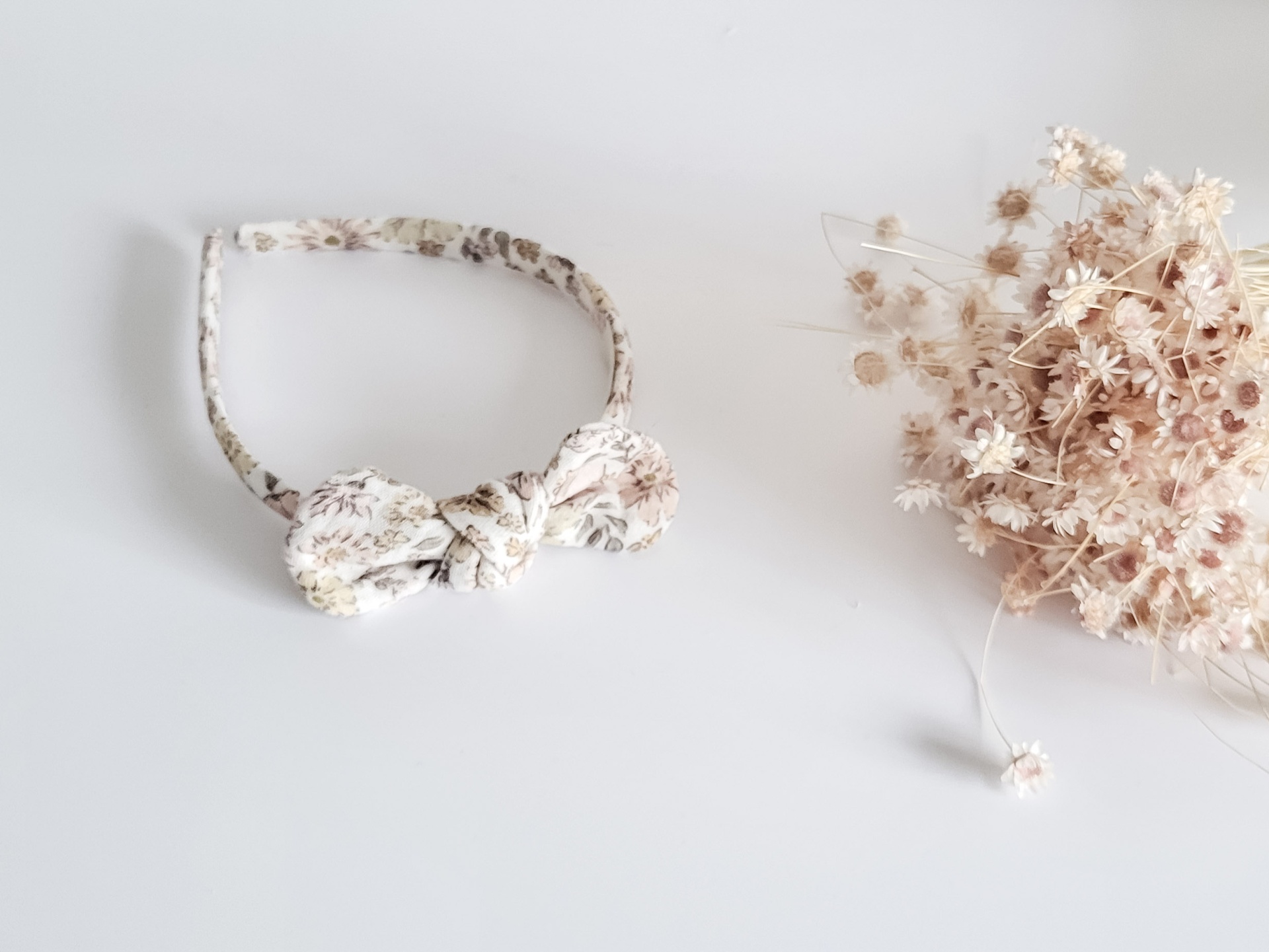 Faixa de cabelo floral e flores secas sobre superfície branca