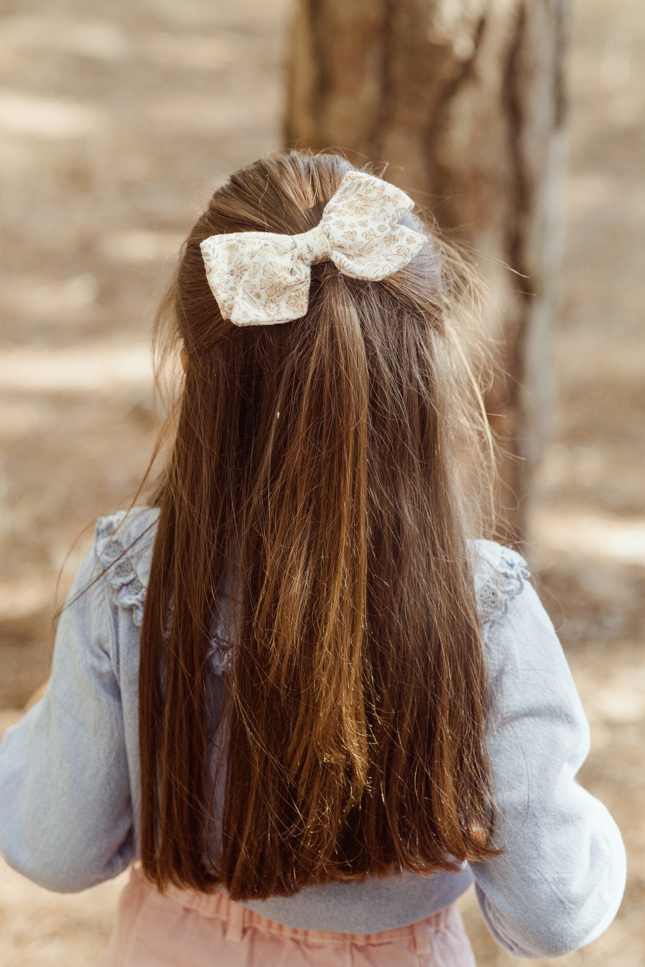 Laço de cabelo branco floral em criança com cabelo castanho comprido