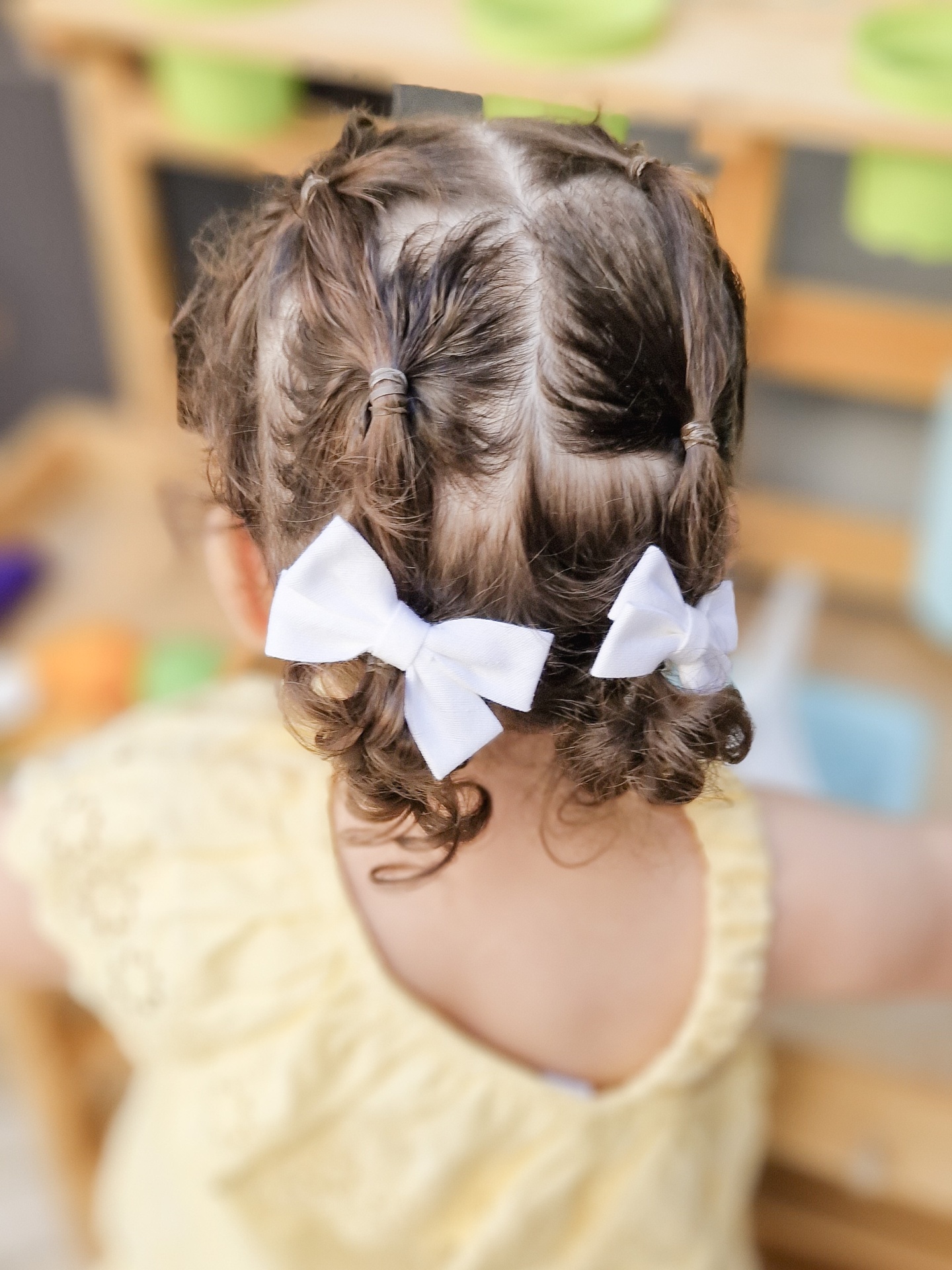 Presilha de cabelo branca com laço em cabelo de criança encaracolado, vista de trás