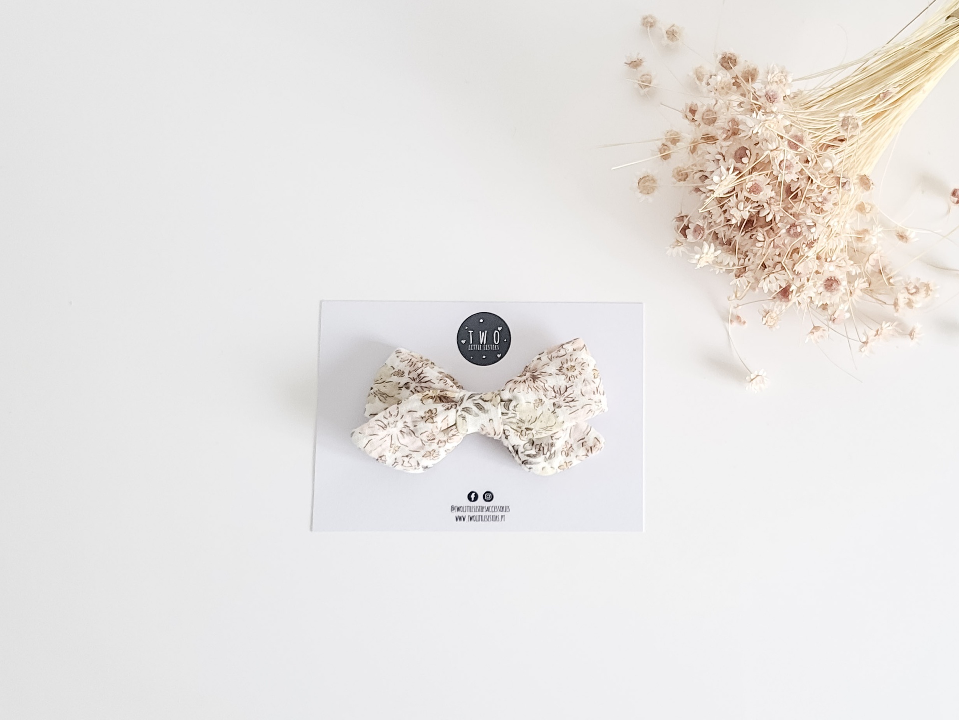 Laço de tecido floral em cartão branco com ramo de flores secas ao lado