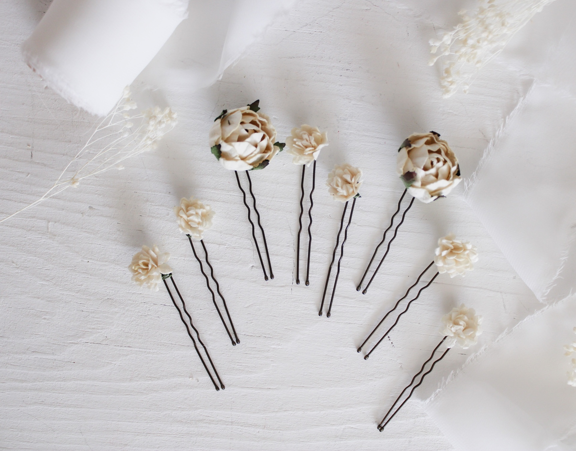 Ganchos de cabelo com flores artificiais castanhas e bege sobre fundo branco