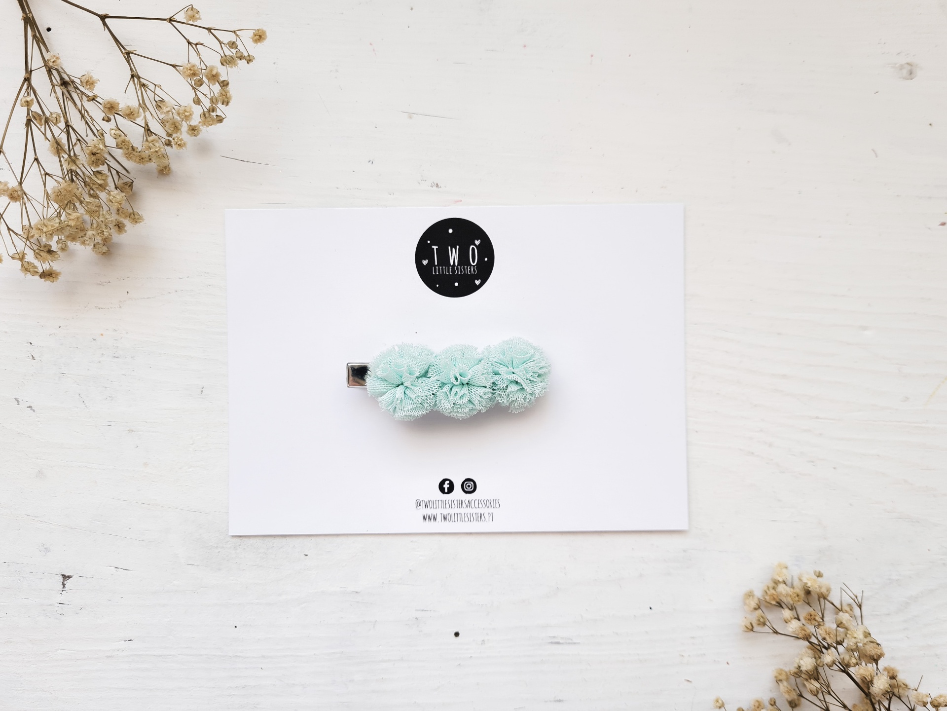 Presilha de cabelo verde água com pompons em cartão branco e flores secas