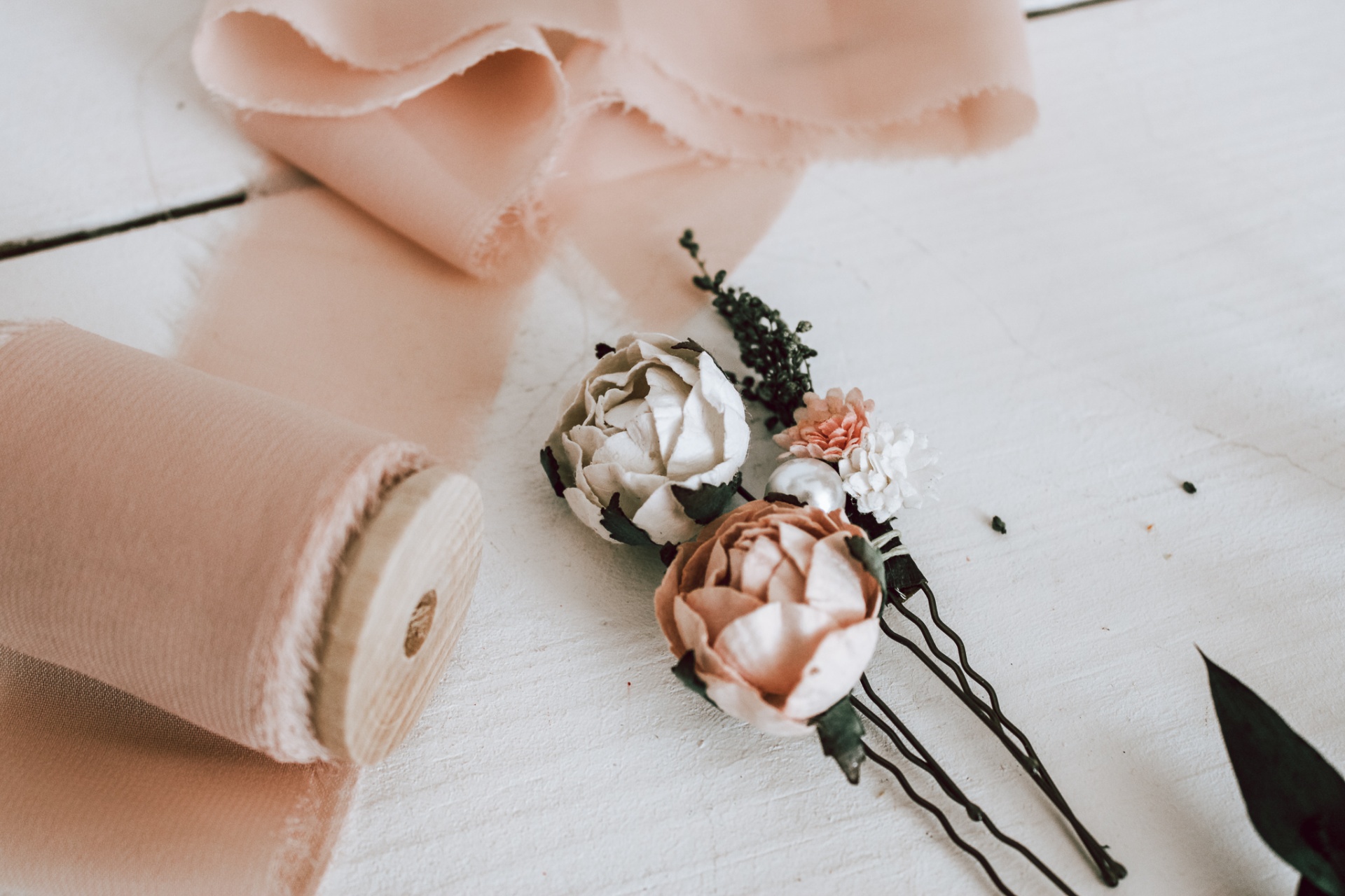 Tecido cor de rosa e ganchos de cabelo florais sobre superfície branca