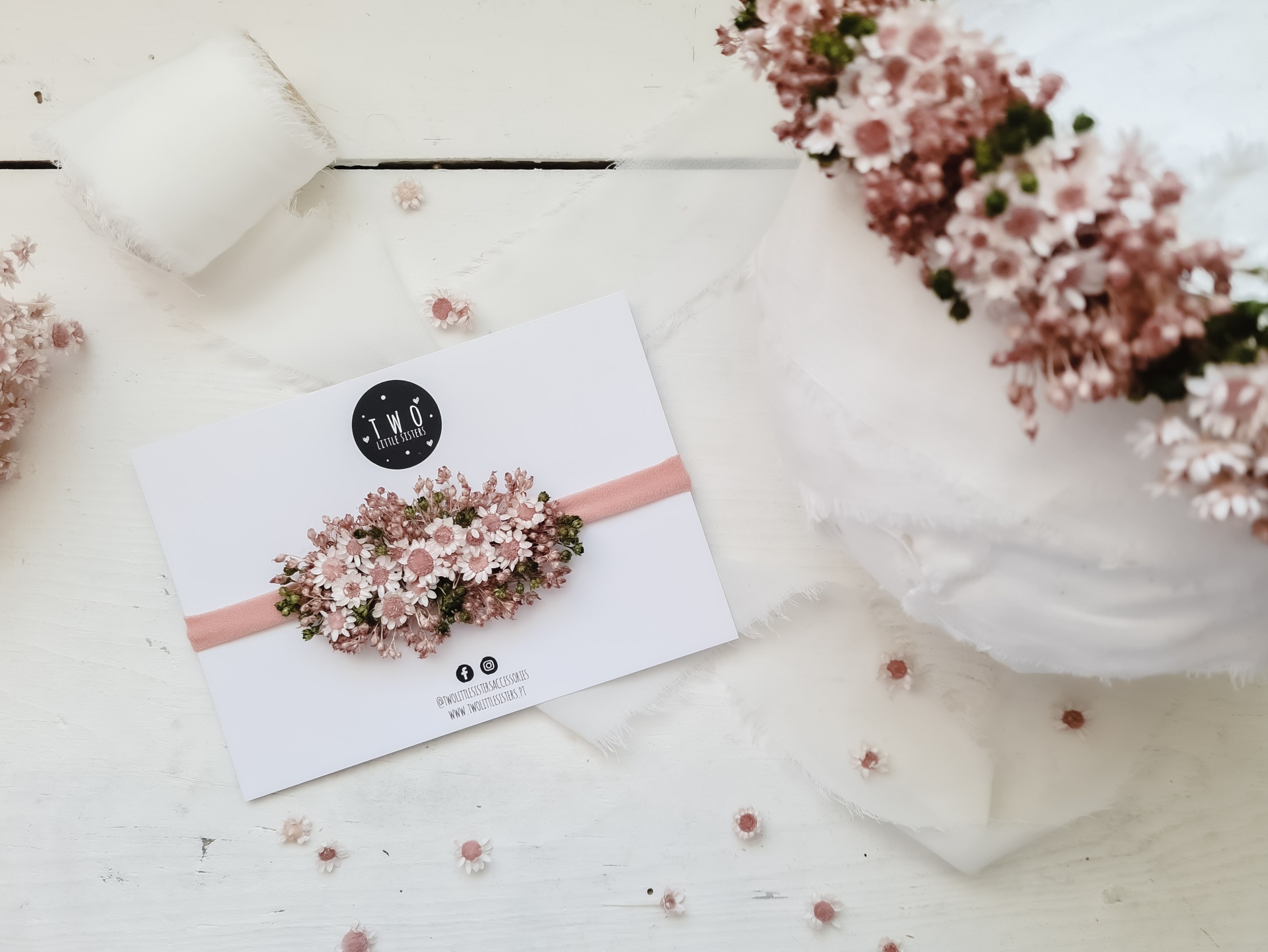 Faixa de cabeça decorada com flores cor-de-rosa e verde em cartão branco com logótipo TKO