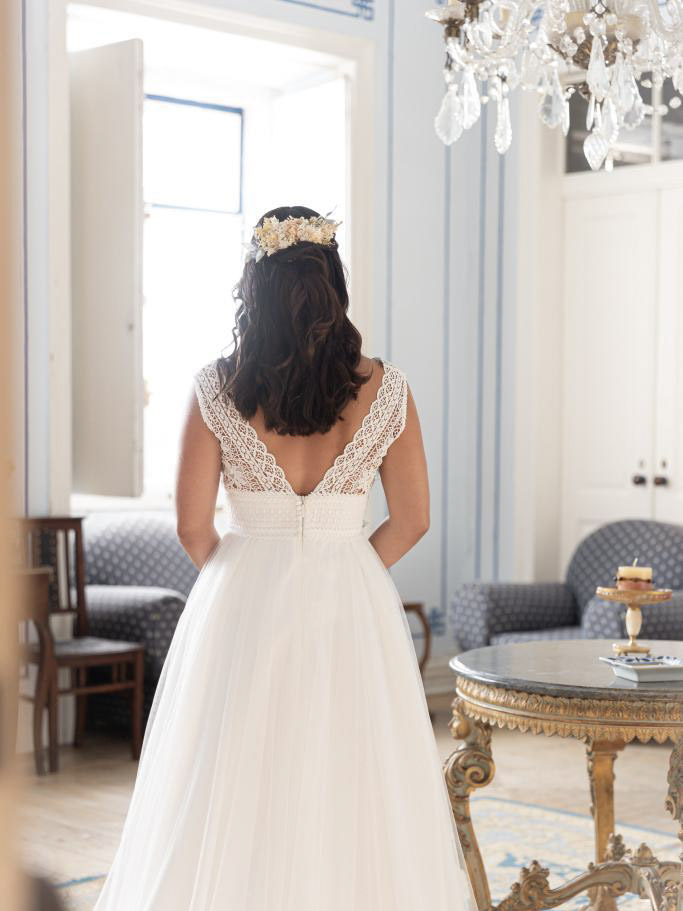 Vestido de noiva branco de costas com corpete de renda e saia fluida em ambiente clássico