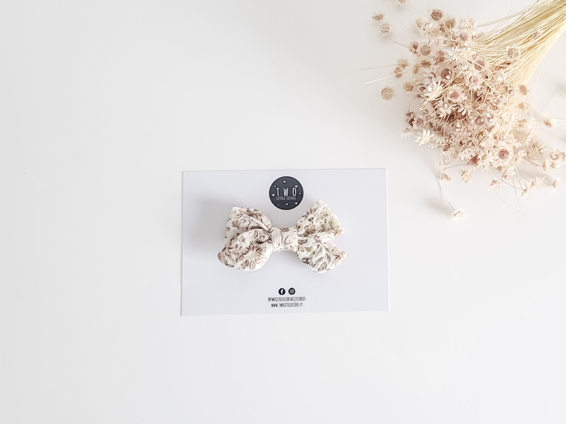 Laço floral bege numa cartão branco e flores secas ao lado