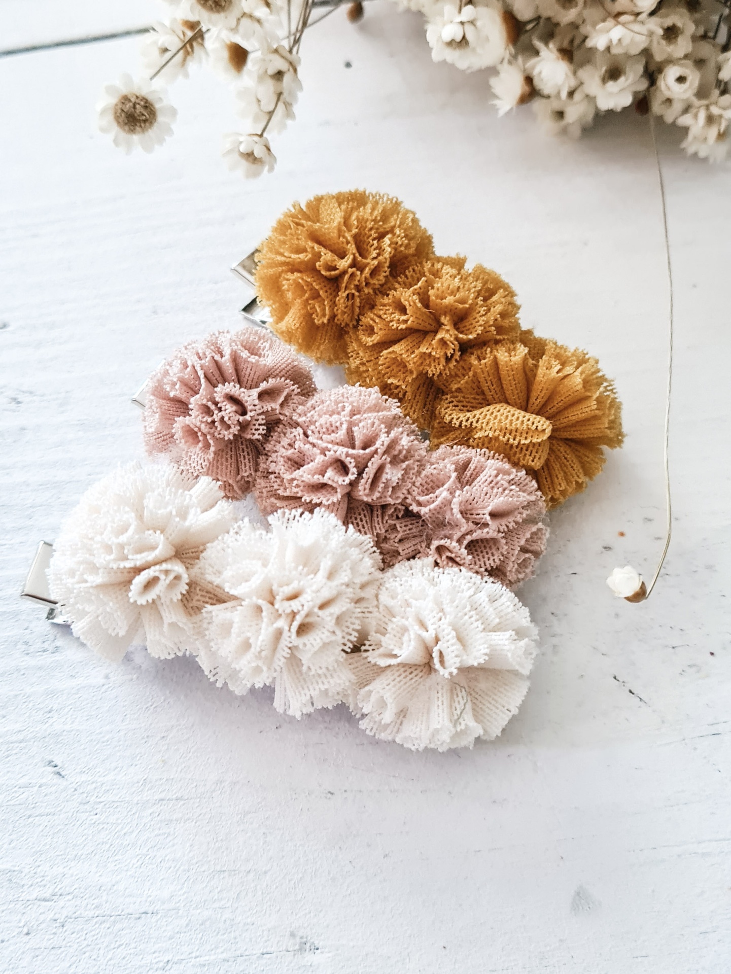 Três molas de cabelo tipo pompom em tecido de renda nas cores mostarda, rosa claro e branco