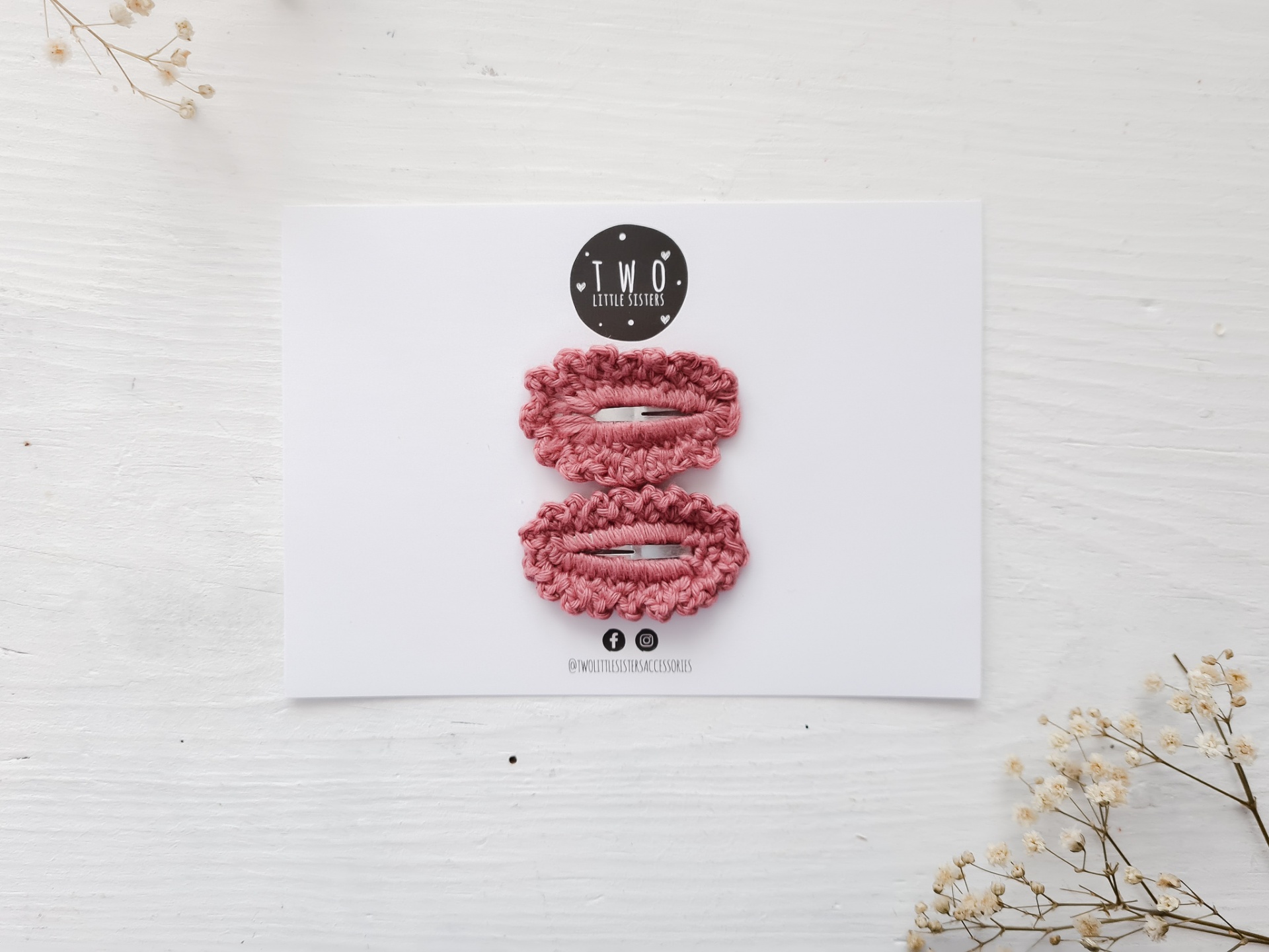 Duas presilhas de cabelo cor-de-rosa em cartolina branca com etiqueta da marca