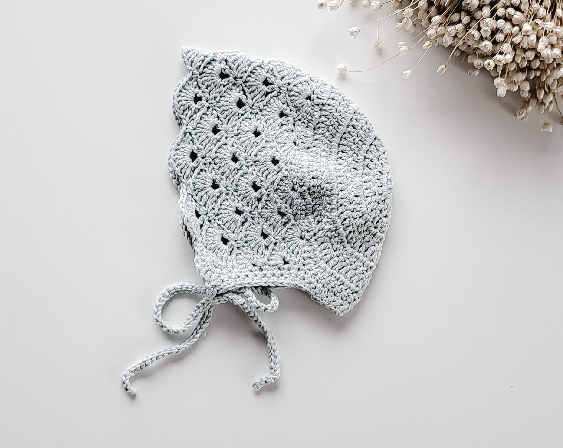 Touca de croché cinzenta clara com padrão de ondas e laços para amarrar