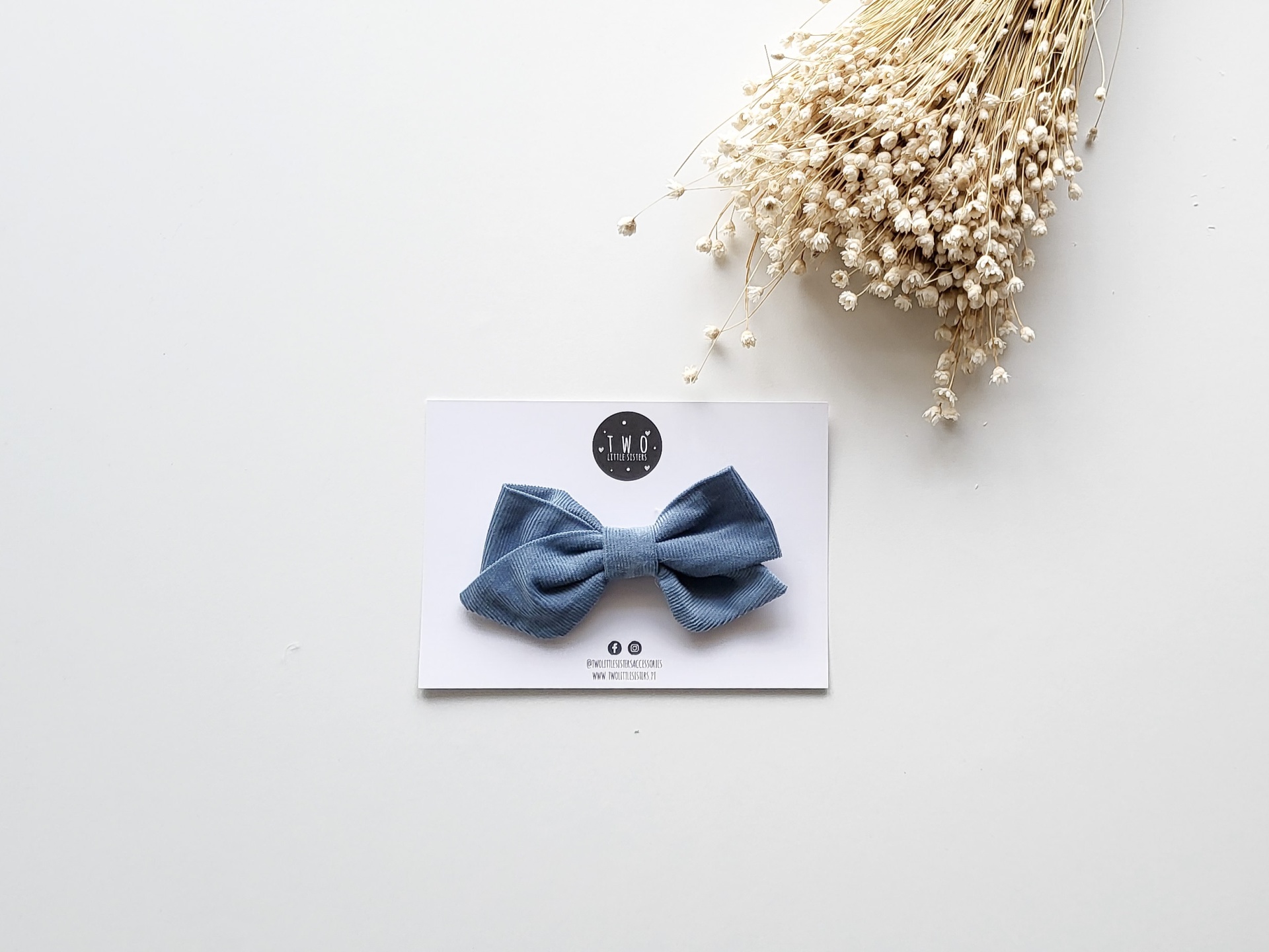 Laço azul em cartão branco com flores secas