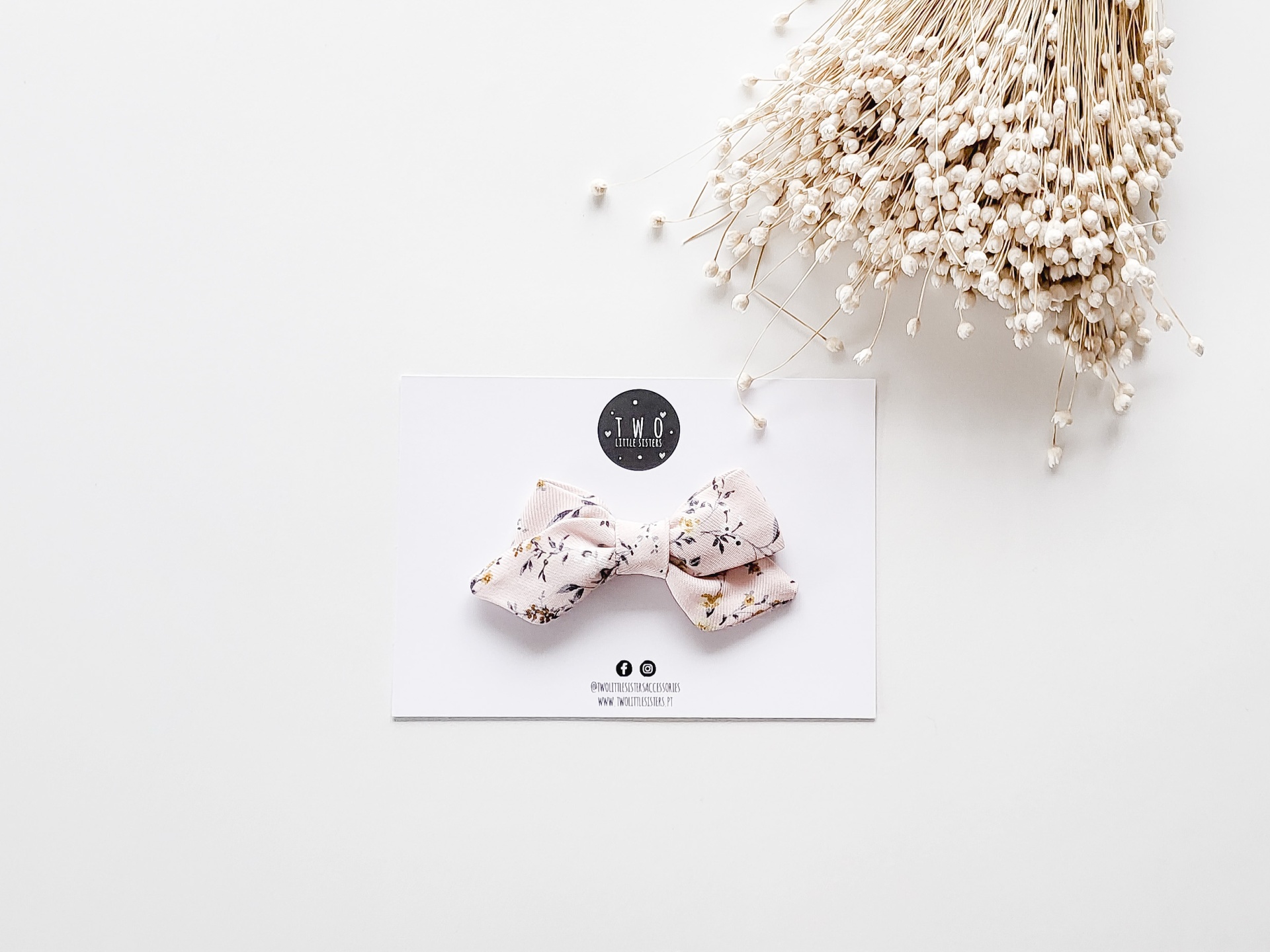 Laço para cabelo bege com padrão floral em cartão branco e flores secas