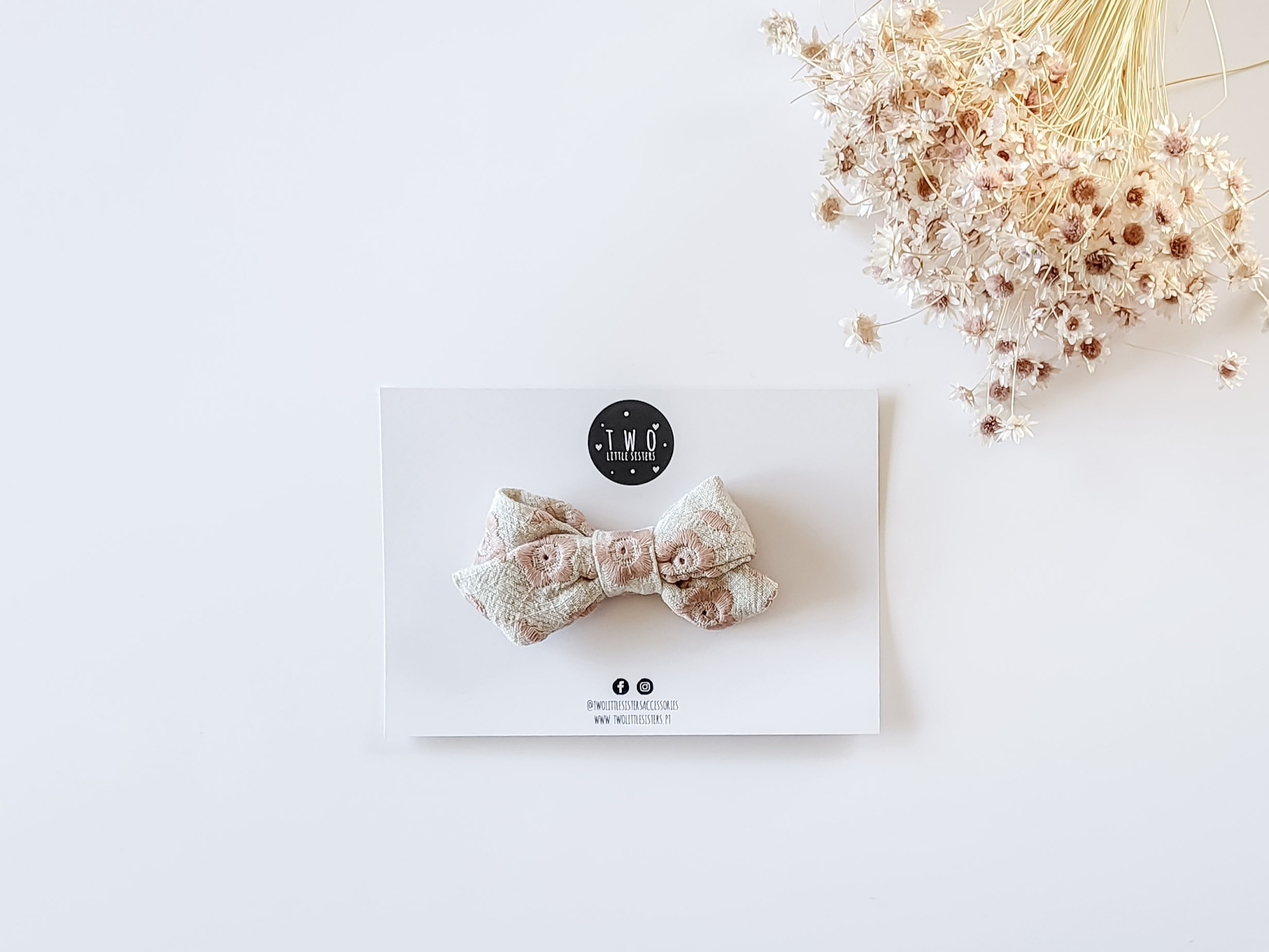 Laço de tecido floral em cartão branco com flores secas ao lado