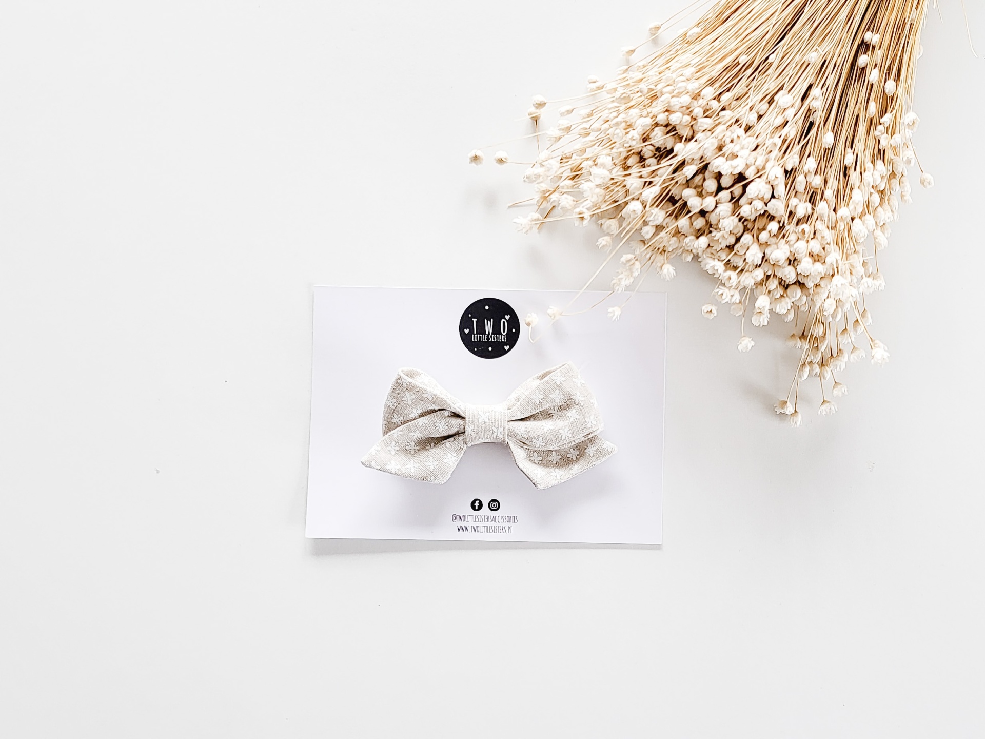 Laço de tecido cinzento claro com padrão discreto apresentado num cartão branco