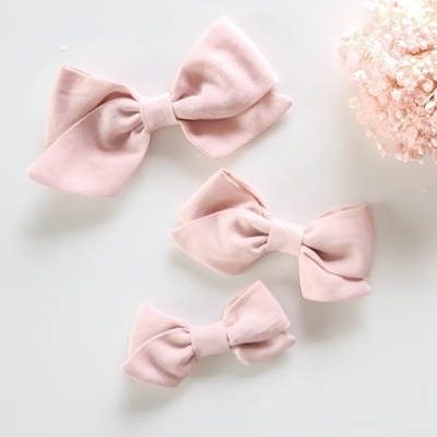 Laços de tecido cor-de-rosa claro em diferentes tamanhos junto a flores secas cor-de-rosa.