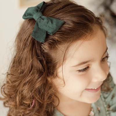 Laço verde escuro no cabelo encaracolado de menina