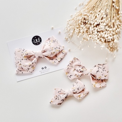 Laços de cabelo rosa com padrão floral e flores secas brancas