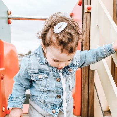 Criança com casaco de ganga e chupeta em parque infantil