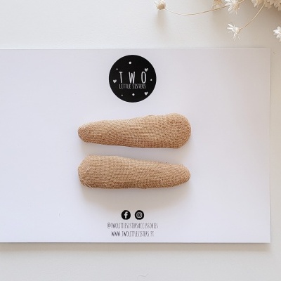 Duas presilhas de cabelo castanhas sobre um cartão branco com texto e selo preto