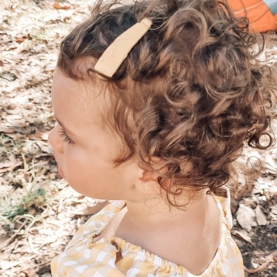 Criança com clipe bege no cabelo e blusa xadrez amarela e branca