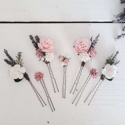 Pentes de cabelo com flores artificiais rosas, brancas e lavanda sobre madeira branca