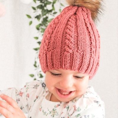 Bebé com gorro rosa tricotado com pompom e camisa floral