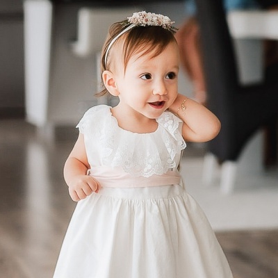 Criança com vestido branco rendado e fita prateada no cabelo