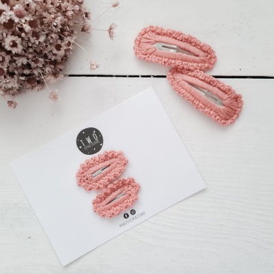 Presilhas de cabelo rosa felpudo em cartão branco com flores secas rosa ao lado