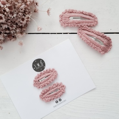 Quatro ganchos de cabelo rosa com textura felpuda sobre fundo branco