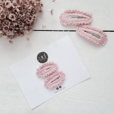 Quatro molares de cabelo rosa em tecido felpudo sobre cartoes brancos e mesa branca com ramo de flores secas