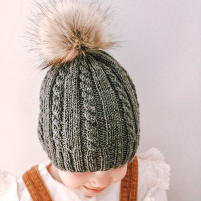 Gorro de malha verde-acinzentado com pompom castanho claro numa criança