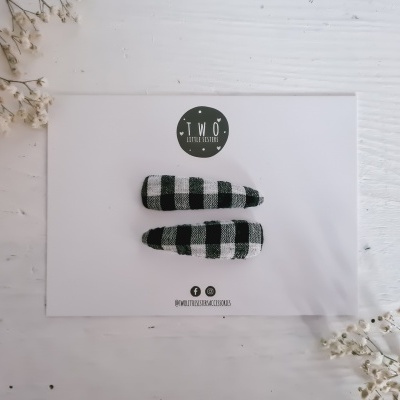 Dois ganchos de cabelo xadrez preto e branco em cartão branco com logótipo circular T.W.O