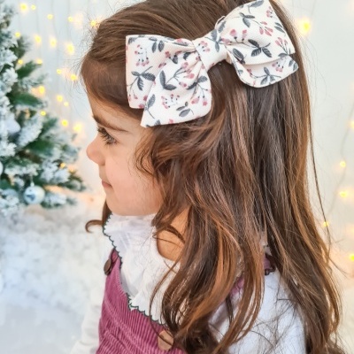 Menina de perfil com laço decorativo no cabelo e fundo de Natal iluminado
