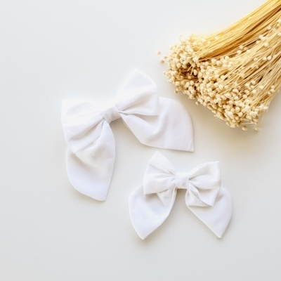 Dois laços brancos de tecido e ramo de flores secas claras sobre fundo branco