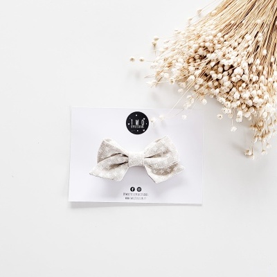 Laço de tecido cinzento claro com padrão discreto apresentado num cartão branco