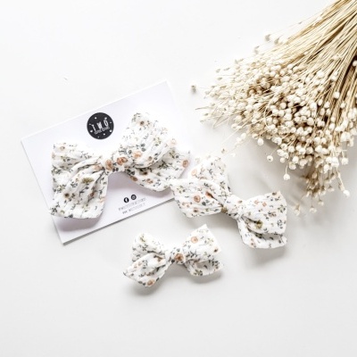 Dois laços de tecido floral branco com ramo de flores secas