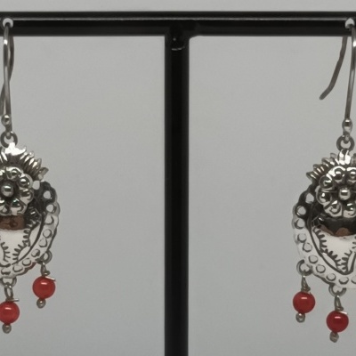 Brincos pendentes de metal prateado com contas vermelhas num suporte preto