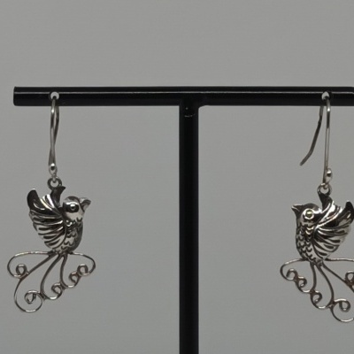Brincos prateados em forma de pássaros com asas detalhadas e cauda em espiral