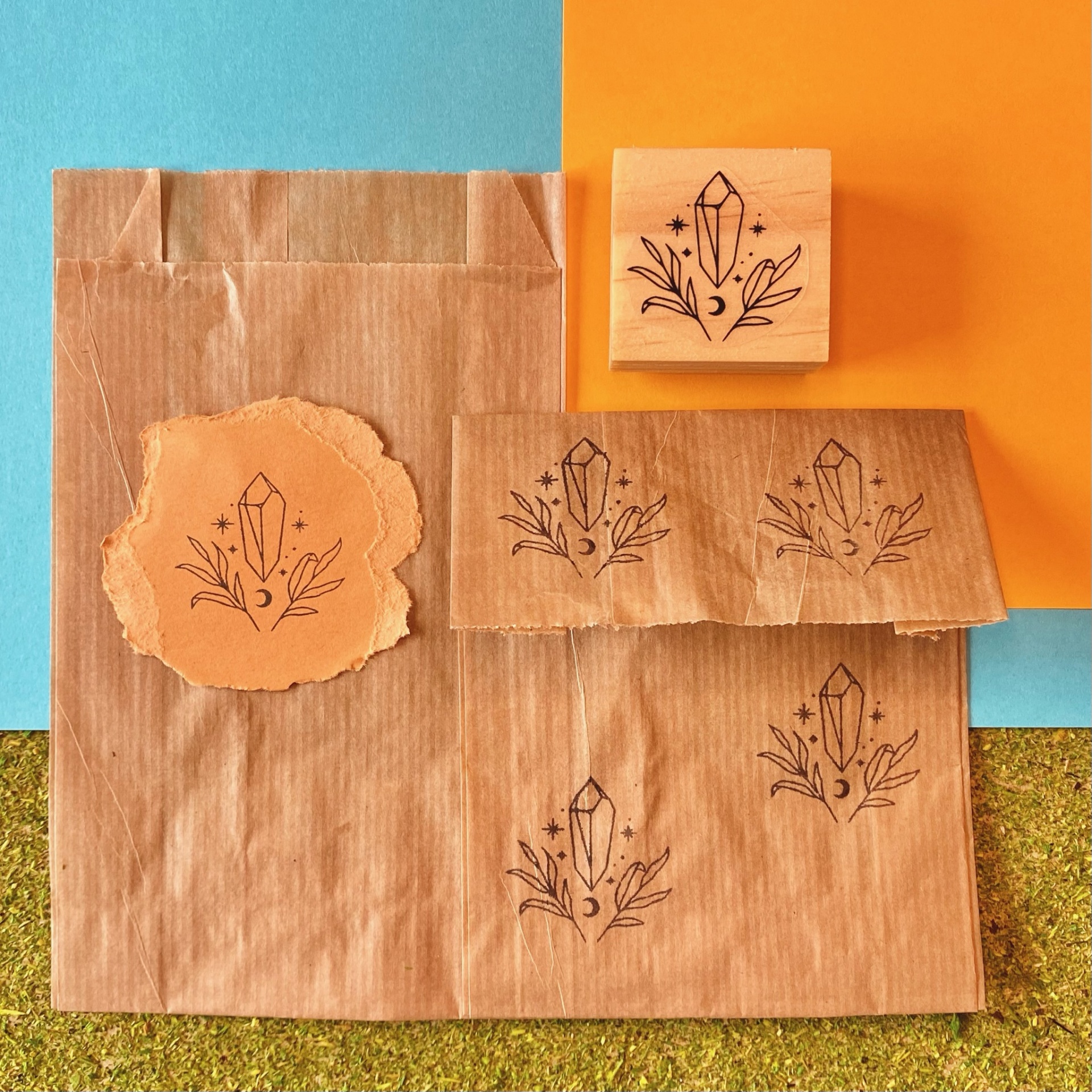 Carimbo de madeira com desenho de cristal e folhas em papel castanho e rasgado