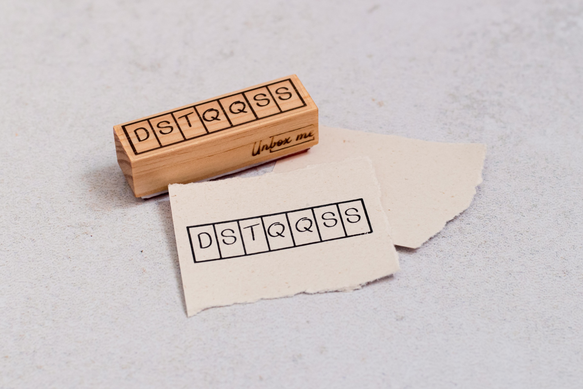 Carimbo de madeira com letras DSTQQSS e impressão num papel branco