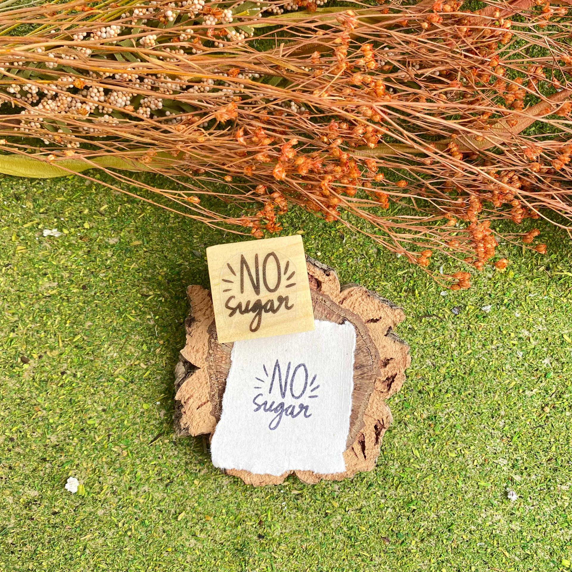 Cartões com texto NO sugar sobre madeira e relva com ramos secos ao fundo
