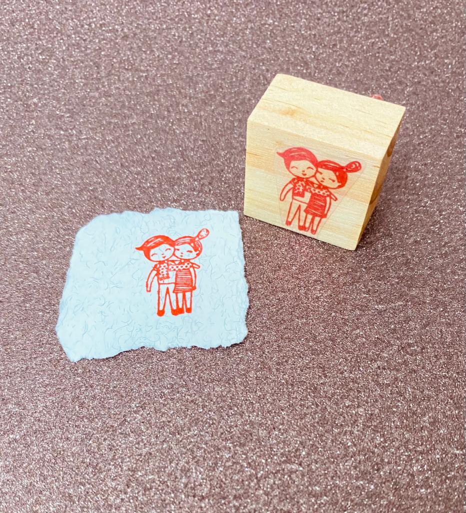 Carimbo de madeira com imagem vermelha e papel com impressão da mesma imagem