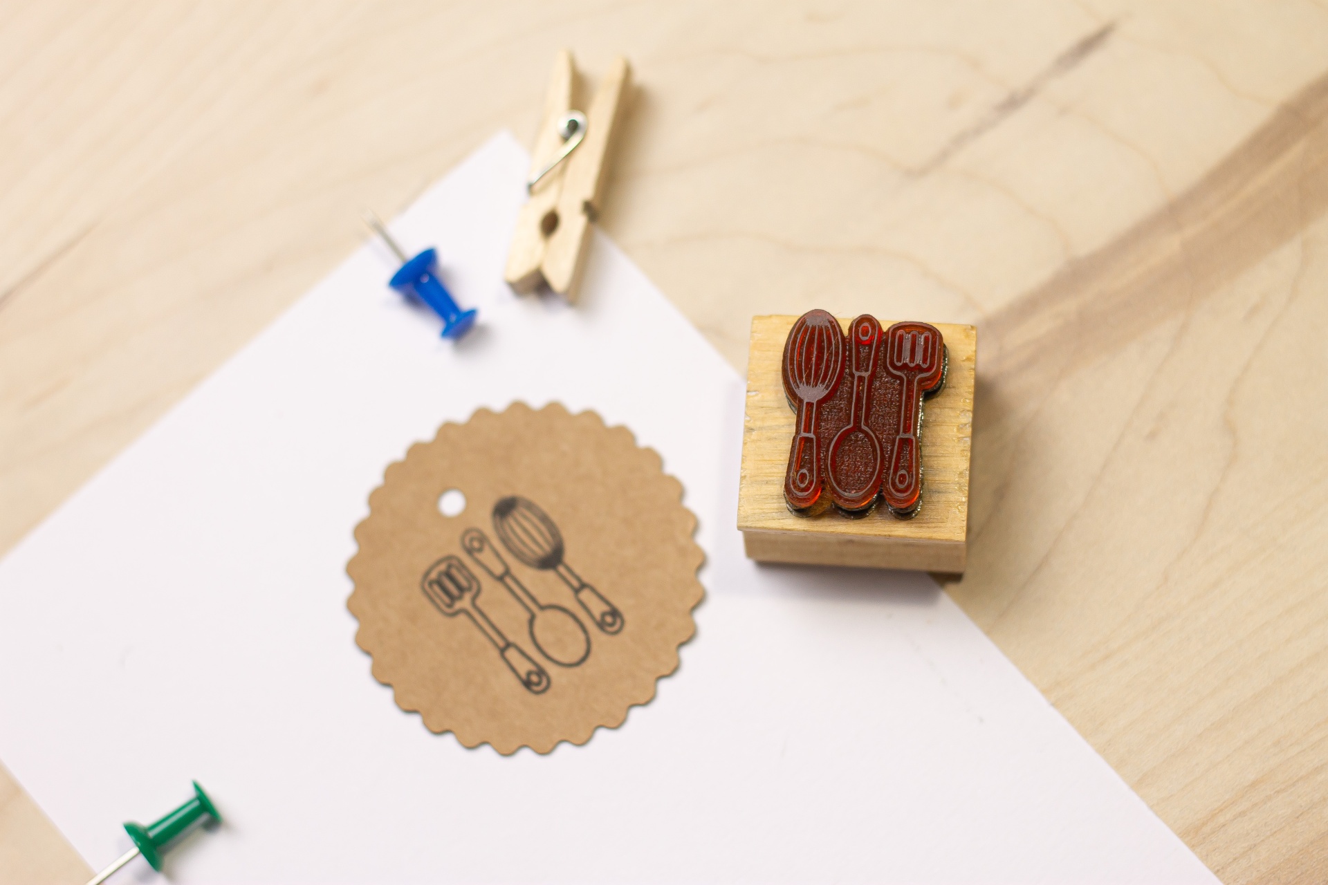 Carimbo de madeira com padrão de talheres e papel recortado com o mesmo padrão